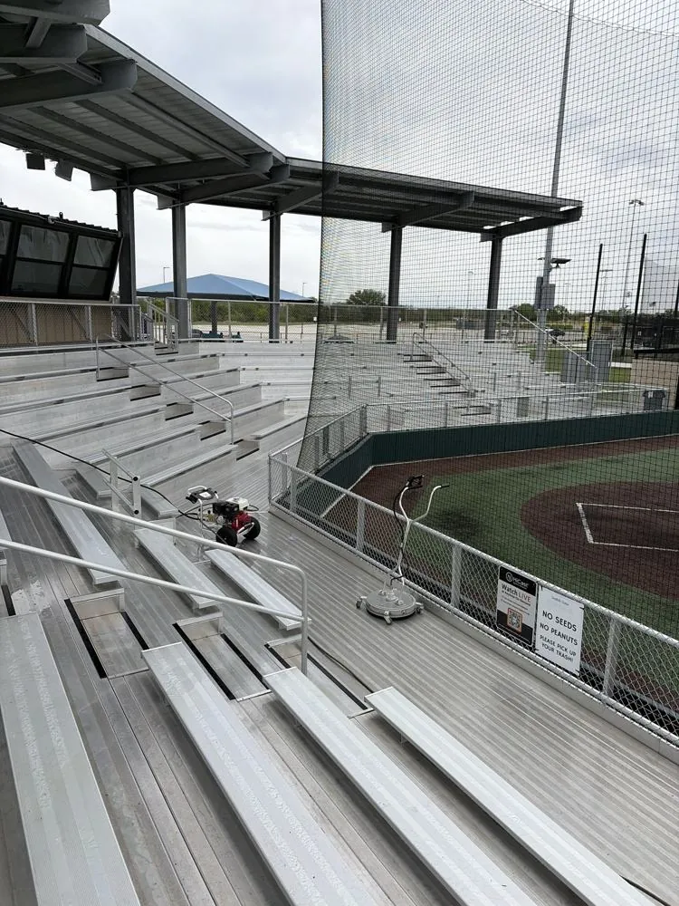 Stadium bleachers being pressure washed with a surface cleaner
