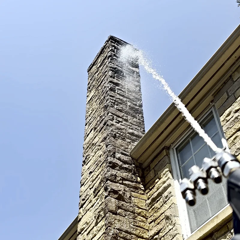 A soft wash stream reaching the top of a stone chimney from the ground