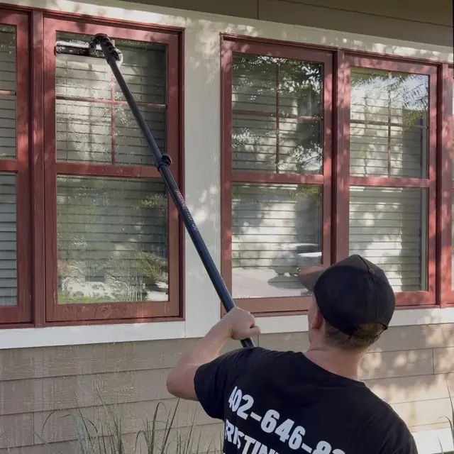 A Pristine Panes technician cleaning a window with a water-fed pole